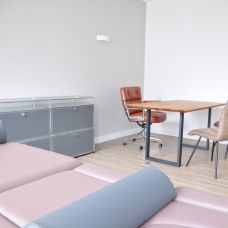 Behandlungsraum mit Schreibtisch und Therapieliege
